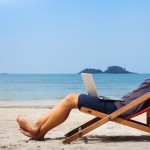 Digital nomad working on his laptop on the beach
