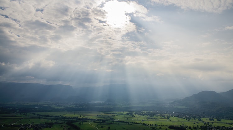Sun rays shining through the clouds onto a city with green grass around