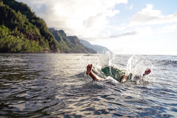 A man splashing in water with trees on an island in the background