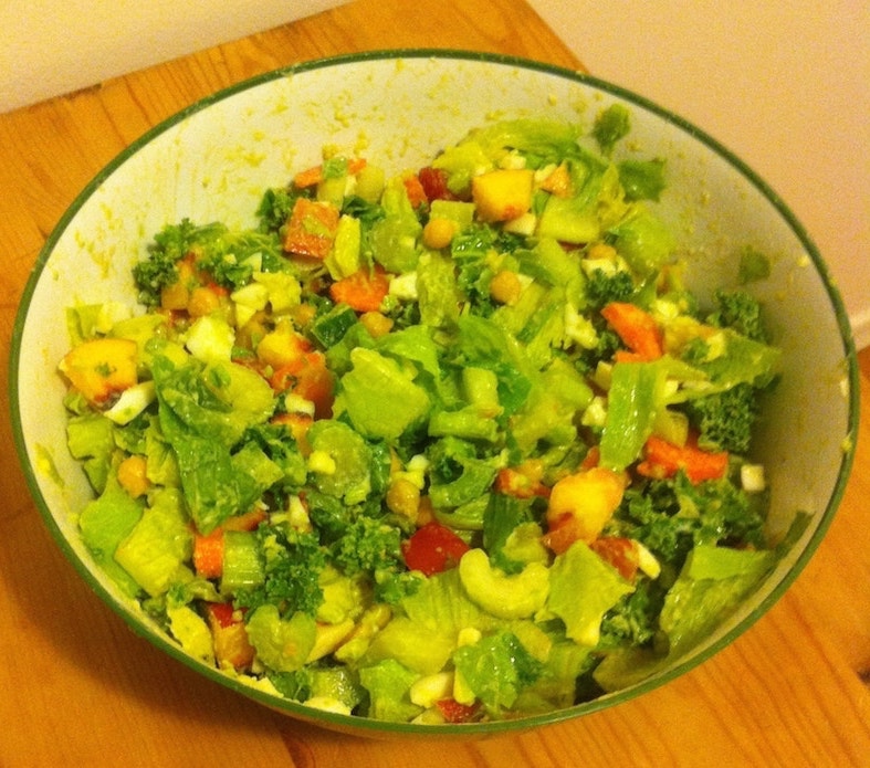 A large salad with greens, chickpeas, peach, cheese, boiled eggs, avocado and olive oil