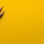 two grey pencils on a yellow background
