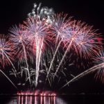 Purple fireworks against a black background on the bay